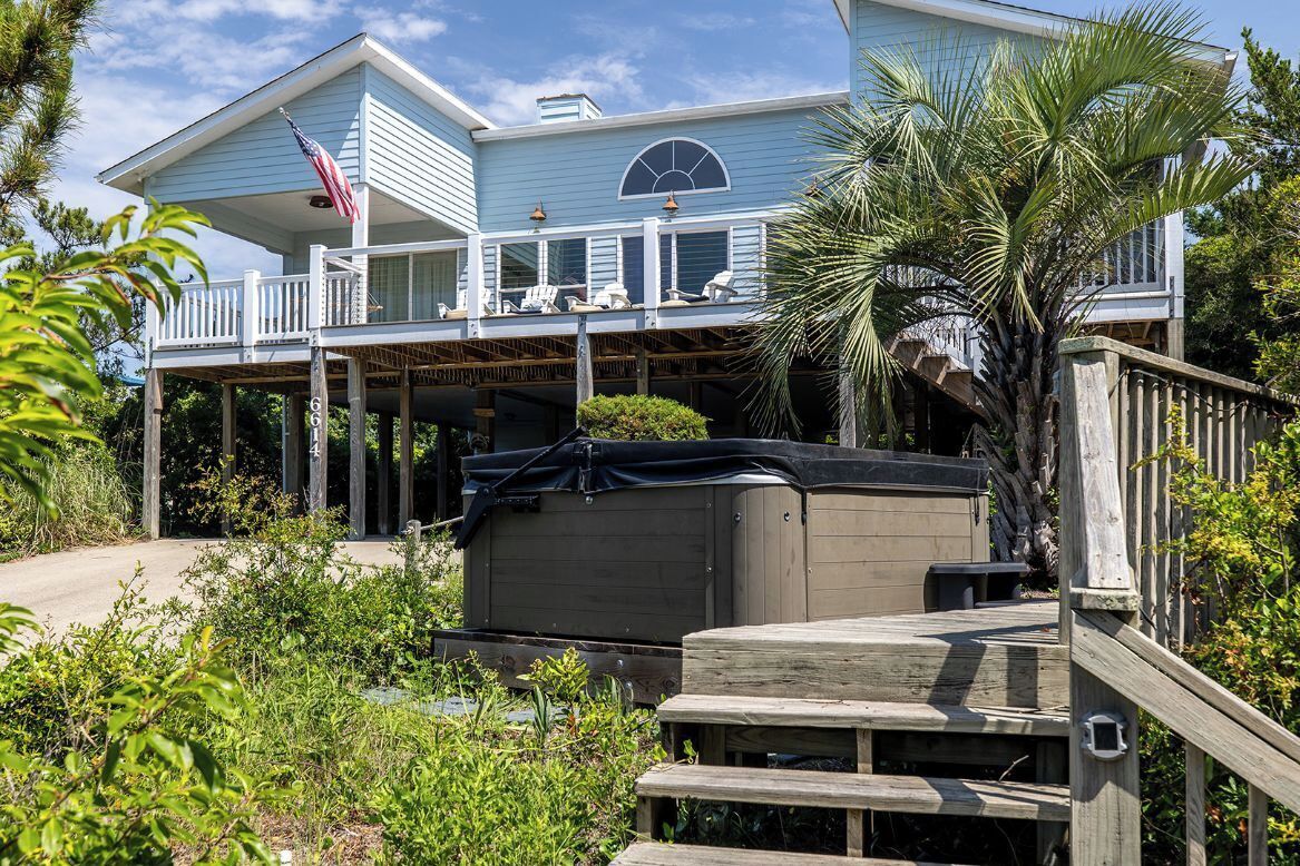 A two-story house with a balcony, a hot tub, and a wooden deck.