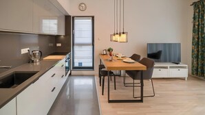 A modern kitchen with a built-in oven, a coffee maker, and a dining area with a wooden table and chairs.