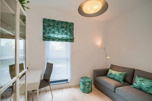 Un salon moderne avec un canapé gris, un bureau blanc et un mur d’accent vert.