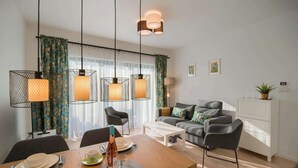A modern living room with a dining area, featuring a sofa set, a coffee table, and pendant lights.