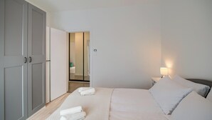 A hotel room with a bed, a wardrobe, a nightstand, and a bathroom visible through an open door.