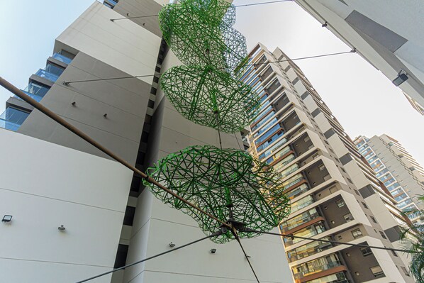 Un edificio de gran altura con diseño moderno, destacando un elemento estructural verde único en primer plano.