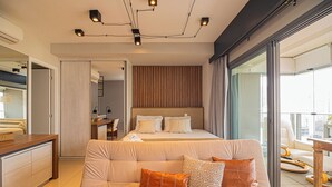 A modern hotel room with a large bed, a sofa, and a dining area.