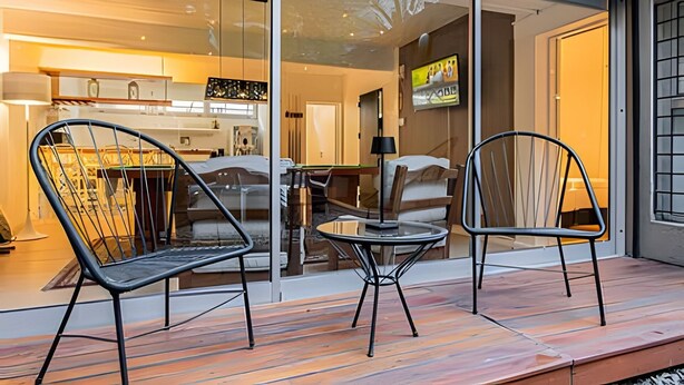 A modern interior with a glass door leading to a kitchen and dining area. There are two black metal chairs and a small round table on a wooden deck. - The Ultimate Palermo Soho Oasis BBQ and Jacuzzi! (Buenos Aires)