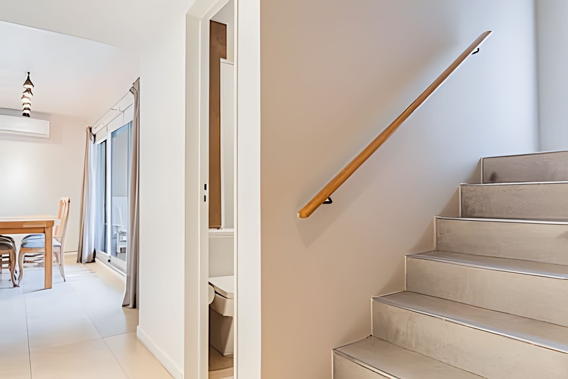 Un escalier avec une rampe en bois et des marches de couleur beige.