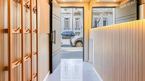 A modern hotel lobby with a wooden reception desk, a glass door leading outside, and a view of the street. - The Ultimate Palermo Soho Oasis BBQ and Jacuzzi! (Buenos Aires)