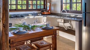 Una cocina con vigas de madera, una mesa de comedor con platos y vasos, y un refrigerador.