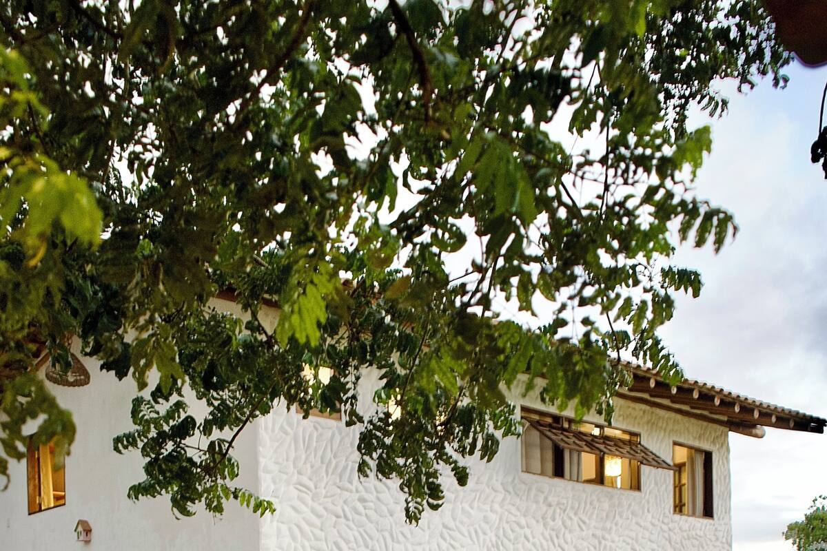 Uma casa de dois andares com piscina, deck de madeira e área de estar ao ar livre.