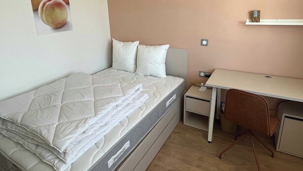Ein gemütliches Schlafzimmer mit Bett, Schreibtisch und Stuhl.