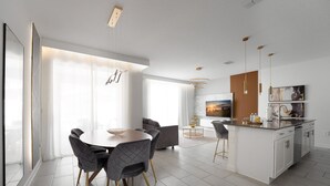 Une cuisine moderne dotée d’un îlot central, de meubles blancs et d’un éclairage suspendu.