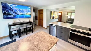 A modern kitchen with a granite countertop, built-in oven, and a large flat-screen TV mounted on the wall. - Great Location close to Resch/Lambeau, Sleeps 14, Huge Game Room, Private Yard (Green Bay)