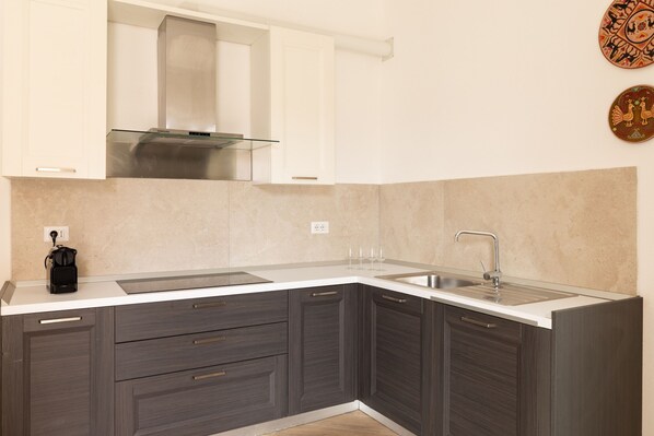 Una cocina moderna con armarios oscuros, una campana extractora de acero inoxidable y un lavaplatos doble.