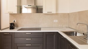 A modern kitchen with white cabinets, a stainless steel sink, and a built-in oven. - Casa Marina con Patio by Wonderful Italy (Olbia)