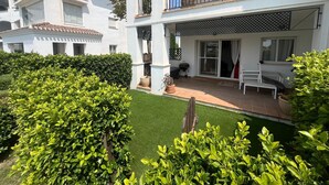 Un immeuble résidentiel à deux étages doté de balcons, d’un patio avec un barbecue et d’un jardin bien entretenu.