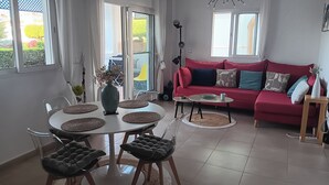 Un salon moderne avec un canapé rouge, une table à manger avec des chaises et une grande fenêtre.