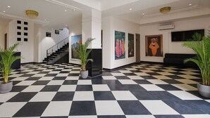 En entréhall med ett schackrutigt golv, en trappa och konstverk på väggarna.