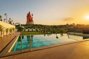 A swimming pool with a statue in the background. - Aarambh By The Sky Imperial (Nathdwara)