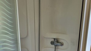 Una ducha con mampara de vidrio, cabezal de ducha y desagüe.