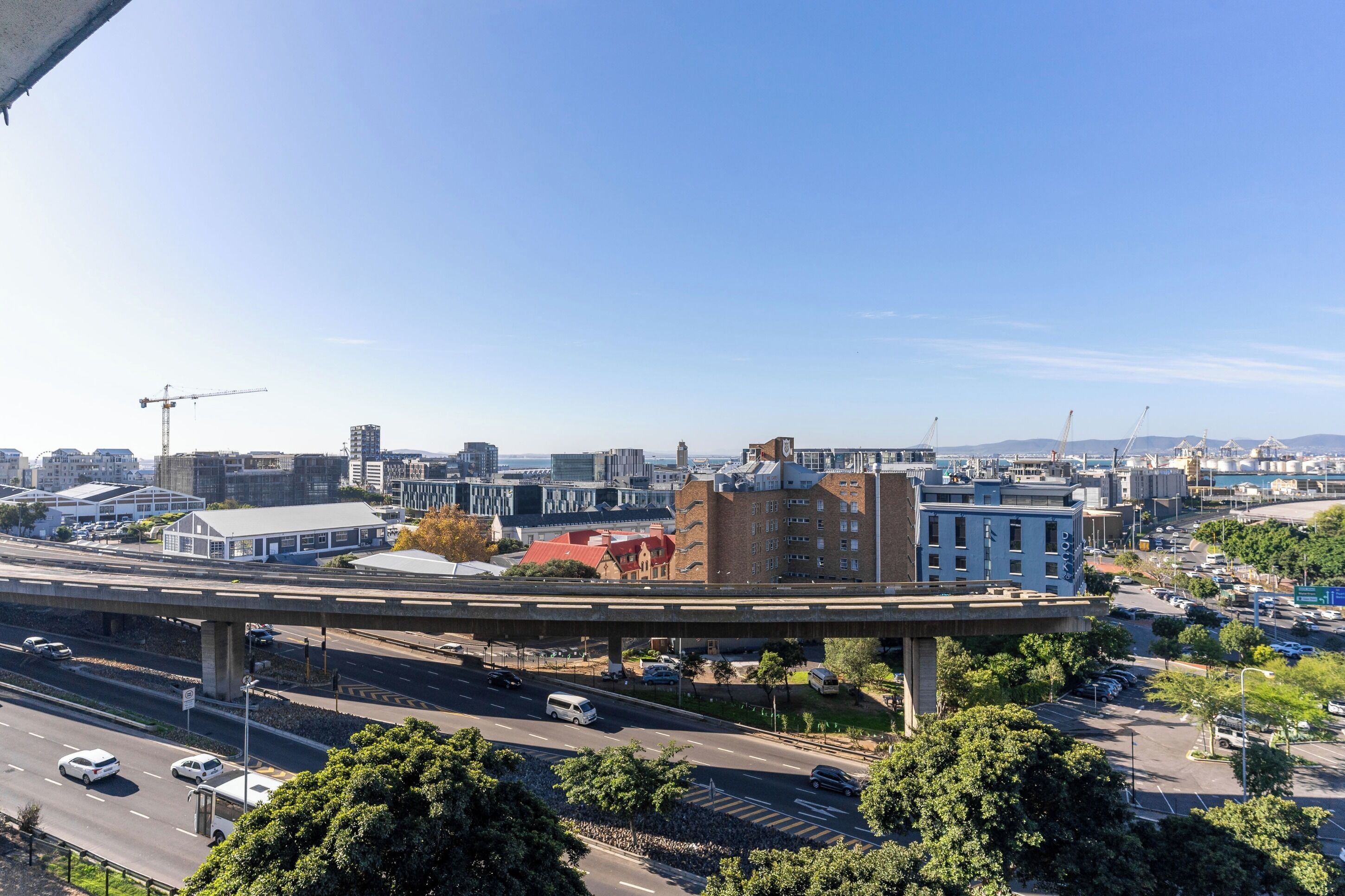 A cityscape with a prominent building, an overpass, and a busy road.