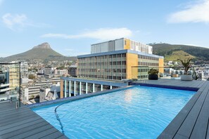 Una piscina sul tetto con vista sulla città e una montagna sullo sfondo.
