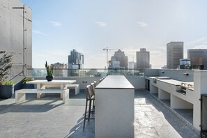 Una terrazza sul tetto con un tavolo lungo, posti a sedere e un angolo bar.