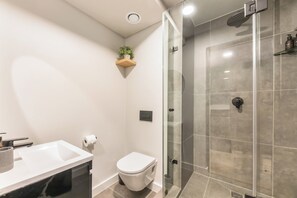 Un bagno moderno con lavandino bianco, servizi igienici e cabina doccia in vetro.