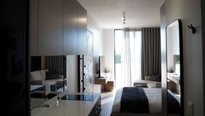 A modern hotel room with a bed, a desk, a chair, and a large mirror.