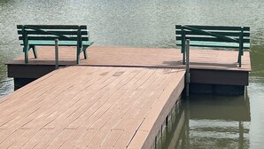 Een houten steiger die uitloopt in een meer, met twee bankjes gericht op het water.