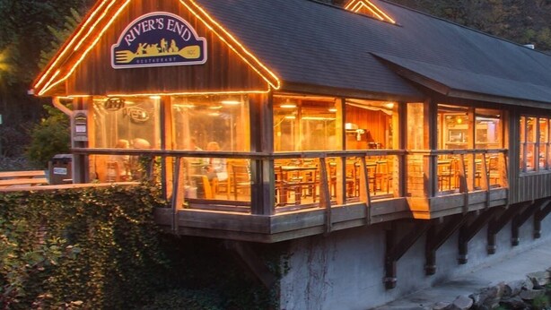Een houten gebouw met een bord waarop staat 'River's End Restaurant'.