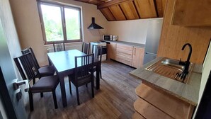 A compact kitchen with a dining area, wooden cabinets, a microwave, and a sink. - Apartmány ŠTĚSTÍ (Bechlin)