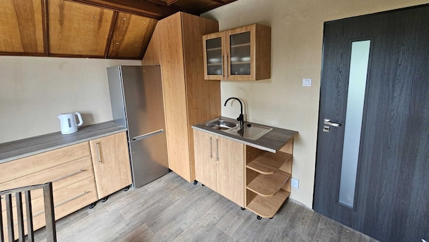 A compact kitchen with wooden cabinets, a built-in sink, and a refrigerator. - Apartmány ŠTĚSTÍ (Bechlin)