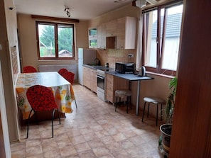 A kitchen with a dining table, chairs, cabinets, a microwave, and a window.