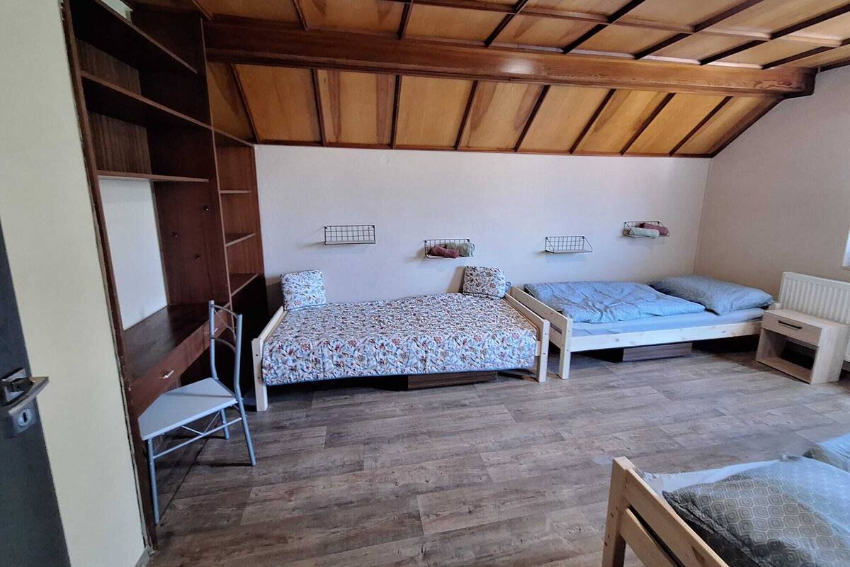 Habitació petita i acollidora amb dos llits, sostre de fusta i un radiador.