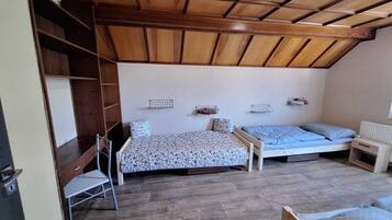 A small, cozy room with two beds, a wooden ceiling, and a radiator.