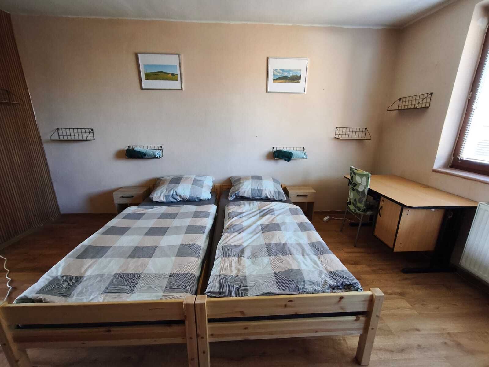 Een kamer met twee houten bedden, een bureau en een stoel.