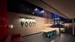 A modern interior with a dining area, a sofa, and a wall with 'FOOD' written on it.