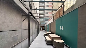 A narrow alleyway with a green wall marked with the number 14, benches, and a mesh fence.