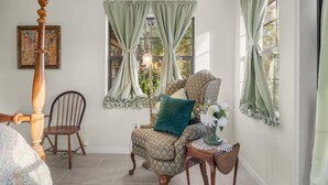 A room with a patterned armchair, a wooden chair, a table with a vase, and a floor lamp. - Vintage Fall retreat Near Springs Cozy Fireplace
(Williston)
