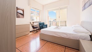Een slaapkamer met een bed, een stoel, een raam en een deur.
