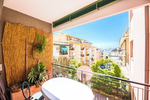 Un balcone con vista su una zona residenziale, un muro di bambù e piante in vaso.