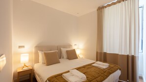 A hotel room with a large bed, two bedside tables with lamps, and a window with curtains. - FLH Glória 70 Flat III (Lisboa ciudad)
