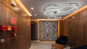 A modern lobby with wooden paneling, a map-patterned wall, a wooden bench, and a blue chair. - FLH Glória 70 Flat III (Lisboa ciudad)