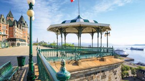 Ein Pavillon mit kanadischer Flagge, ein historisches Gebäude und Blick auf das Wasser.