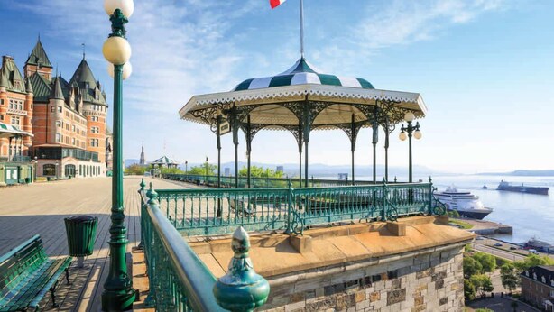 Um gazebo com a bandeira do Canadá, um edifício histórico e vista para a orla marítima.