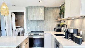 A modern kitchen with a built-in washer and dryer, stainless steel appliances, and a clean, light wood floor. - L Oasis Boheme Hot tub 2 Bedrooms | Free EVCharger (Boischatel)