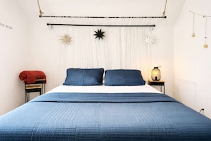 A bedroom with a bed, a nightstand, a lamp, and decorative star-shaped items on the wall.