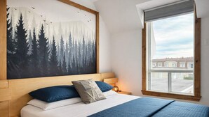 A bedroom with a bed, a painting of a forest, a window with a view, and a nightstand with a lamp. - 2 minutes from the falls | Private terrace | Sleeps 6 (Boischatel)