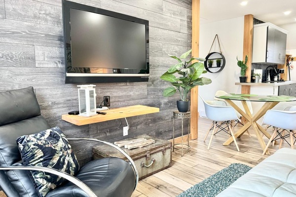 Grand salon avec TĂ©lĂ©vision - un espace Ă©lĂ©gant et confortable, dotĂ© dâun mobilier moderne, dâune grande tĂ©lĂ© et de touches vertes apaisantes.