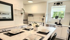 Une cuisine moderne dotée d’un îlot central, de meubles blancs et d’une fenêtre donnant sur un paysage verdoyant.
