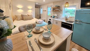 A modern kitchen with a dining area, a blue refrigerator, and a bed with a view.